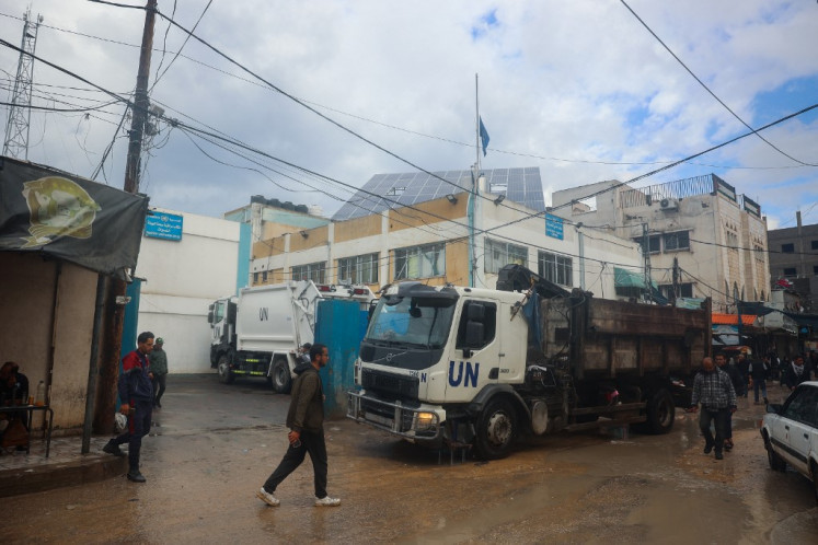 Warga Palestina berjalan di depan kantor Badan Pengungsi Palestina (UNRWA) di Bureij di Jalur Gaza Tengah pada 23 Januari 2025, berhari -hari dalam kesepakatan gencatan senjata dalam perang antara Israel dan gerakan Hamas Palestina.