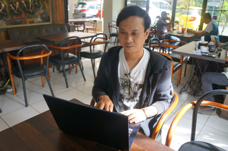 Lecturer Bayu Budiandrian works on his laptop on the sidelines of an interview session with The Jakarta Post at a café in Jakarta on Jan. 15, 2025. Bayu, a civil servant lecturer at Singaperbangsa University in Karawang, West Java, shares his struggles as he has to balance his tasks and obligations with low pay.