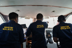 A Malaysian Maritime Enforcement Agency officer (center) points to an object during the rescue operation for missing sailors from the USS John S. McCain off the Johor coast of Malaysia on Aug. 24, 2017.