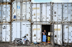A woman with an infant and a toddler stands in the entrance to an empty container on Jan. 31, 2025, in Cilincing, North Jakarta, to where they were evacuated along with other residents of Sepatan village in Rorotan subdistrict after their homes were flooded.