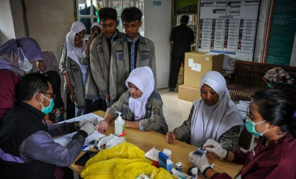 Health workers take blood samples from students on March 2, 2023, during a screening for noncommunicable diseases, including diabetes, at SMP 21 junior high school in Bandung, West Java.