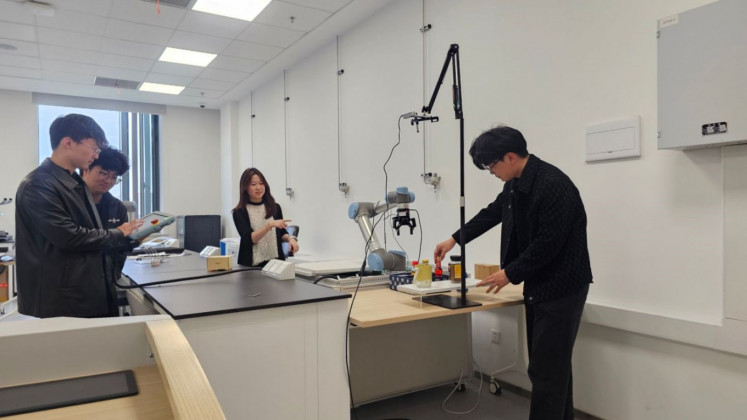 Applied learning: Clarine Beryl (second from right) and her team members work on software development with a robotic arm at a lab.