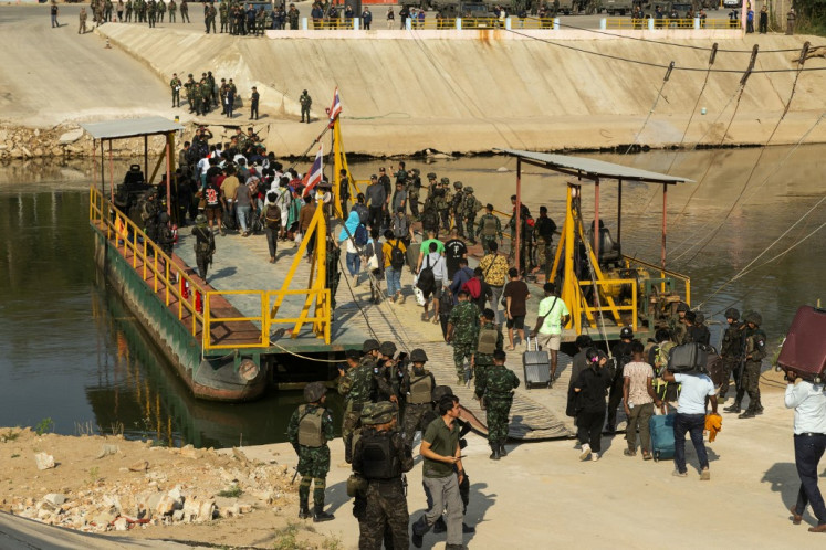 Myanmar security forces escort people released from scam centers on Feb. 12, 2025, as they board a river ferry in Kyauk Khet, Myawaddy, to cross the border into Thailand.