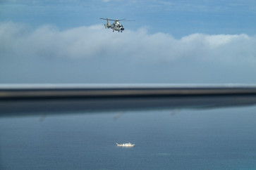 An aircraft identified by the Philippine Coast Guard as Chinese Navy helicopter (R) and a vessel identified by the Philippine Coast Guard as maritime militia (L) are seen during an aerial reconnaissance flight at Scarborough Shoal in the South China Sea on February 18, 2025.
