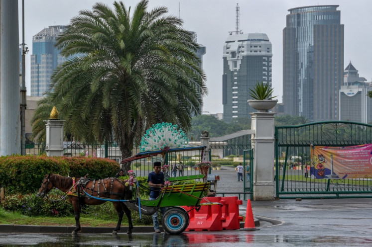A delman (horse-drawn carriage) driver prepares his carriage while waiting for passengers near the National Monument (Monas) park in Jakarta on Jan. 28, 2025. To the eye of a tourist, the delman can appear as a colourful addition to the city, adorned by decorations and small bells that tinkle when the horse moves, but some owners still rely on harmful traditional medications, including puncturing the horse's muscles with bamboo sticks to pass a rope through to “cleanse“ its blood.