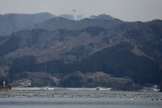 A Japan Self-Defense Force aircraft (top center) sprays water over hilltops as officials continue to fight a wildfire near the city of Ofunato in Iwate Prefecture, Japan on Feb. 28, 2025. Military helicopters have been mobilized to try and douse the flames raging in forested areas of Ofunato.