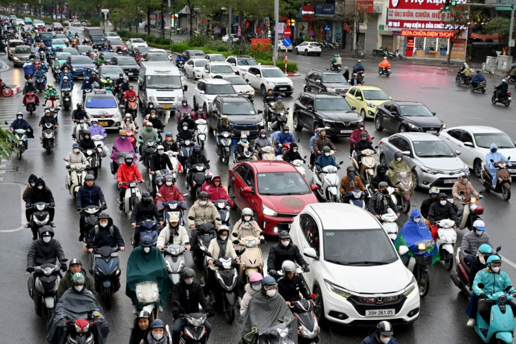 Motorbikes and cars drive on a busy road in Hanoi on Feb. 7, 2025.