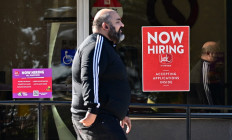 A pedestrian walks past a “Now Hiring“ sign posted on a business storefront in San Gabriel, California, US, on Aug. 21, 2024.