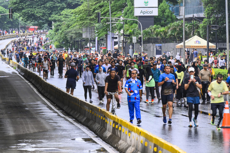 Recreational routines: People exercise in the rain on Feb. 9, 2025, during a car free day at the Hotel Indonesia traffic circle in Central Jakarta.