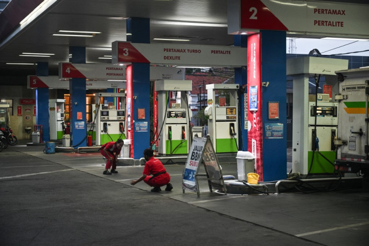 Workers wait for customers at a filling station of state-owned oil company Pertamina in Surabaya on March 4, 2025.

