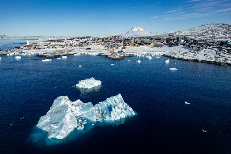This aerial view shows icebergs floating in the waters beaten down by the sun with buildings in the background off Nuuk, Greenland, on March 11, 2025, on the day of Greenland, the autonomous Danish territory, legislative elections.