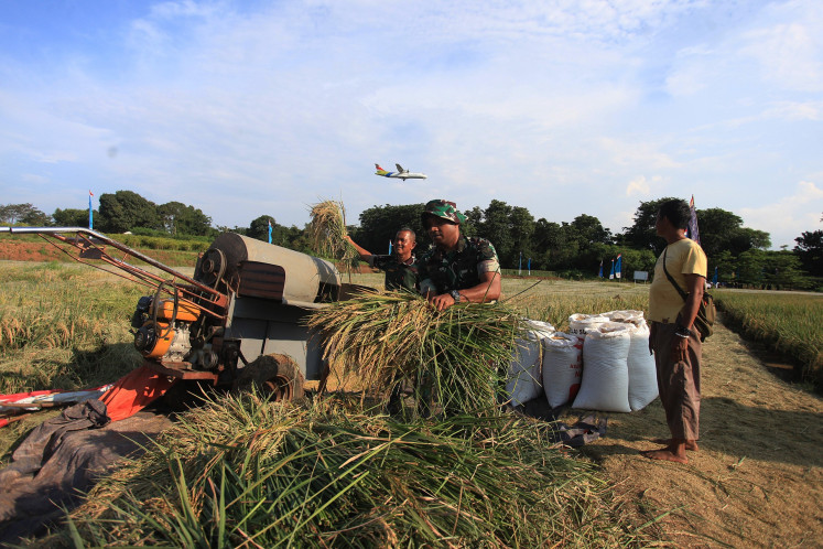 Indonesian Air Force personnel helps a farmer carry harvested rice at a rice field in the Halim Perdanakusuma Air Force Base complex in Jakarta on Feb. 28, 2025.