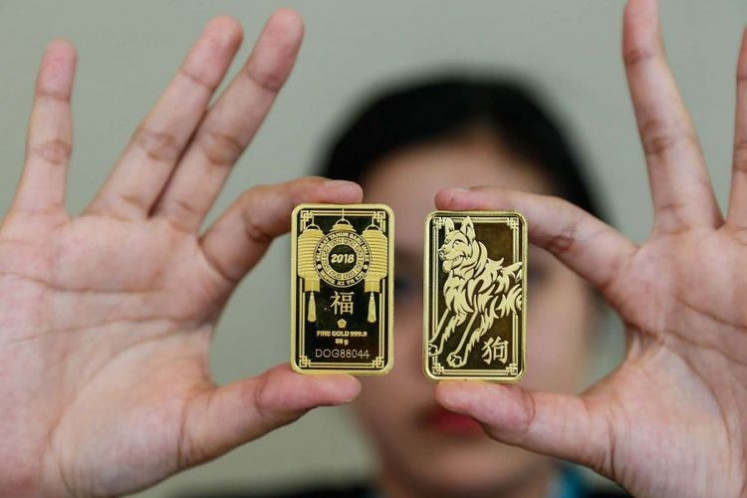 An employee shows two bars of gold produced by State-owned diversified mining company PT Aneka Tambang (Antam).