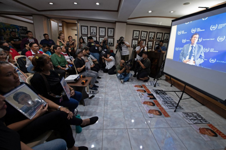 Families, some holding portraits, of victims of former Philippines president Rodrigo Duterte's drug war watch a live stream of Duterte's first appearance at the International Criminal Court (ICC) since his arrest on March 11, during a live viewing at a church building in Manila on March 14, 2025. Duterte failed to show in person at the ICC on March 14 at the opening of his crimes against humanity hearing over his deadly crackdown on narcotics.