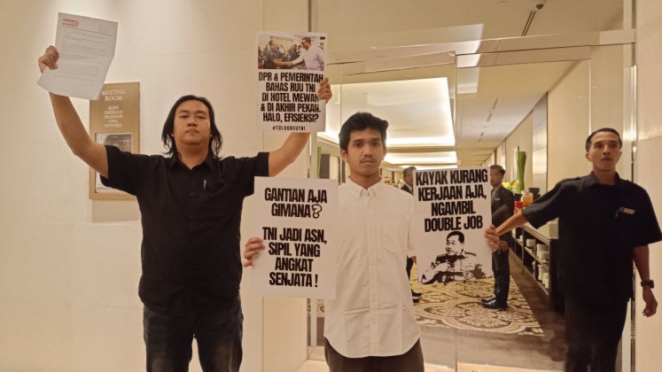 Three activists from the Civil Society Coalition for Security Sector Reform enter a room on Saturday in Jakarta’s Fairmont Hotel, in which a secret, closed-door meeting between the government and members of the House of Representatives took place to discuss revisions to the Indonesian Military (TNI) Law.