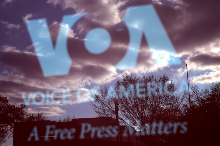 The Voice of America (VOA) sign is seen on the glass window of a bus stop on March 17, 2025 in Washington, DC. President Donald Trump signed an executive order to eliminate the U.S. Agency for Global Media (USAGM), the parent agency of VOA, and put VOA employees on administrative leave. 