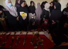 Day of mourning: Family and friends pray next to the coffin of First Brig. M. Ghalib Surya Ganta on March 18 at his family's home in Bandar Lampung. Ghalib is one of three officers killed during a raid at a cockfighting arena in Way Kanan regency in Lampung.