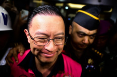 Thomas Lembong (left), wearing a detainee jacket, is escorted from the Attorney General's Office on Oct. 29, 2024, after he was named a graft suspect for allegedly embezzling Rp 400 billion (US$25.39 million) from a sugar import project during his time as trade minister from 2015 to 2016. 

