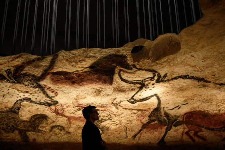A vsitors looks at a section of the life size Lascaux cave replica after a special immersive torch light visit on June 16, 2022 in Montignac. 