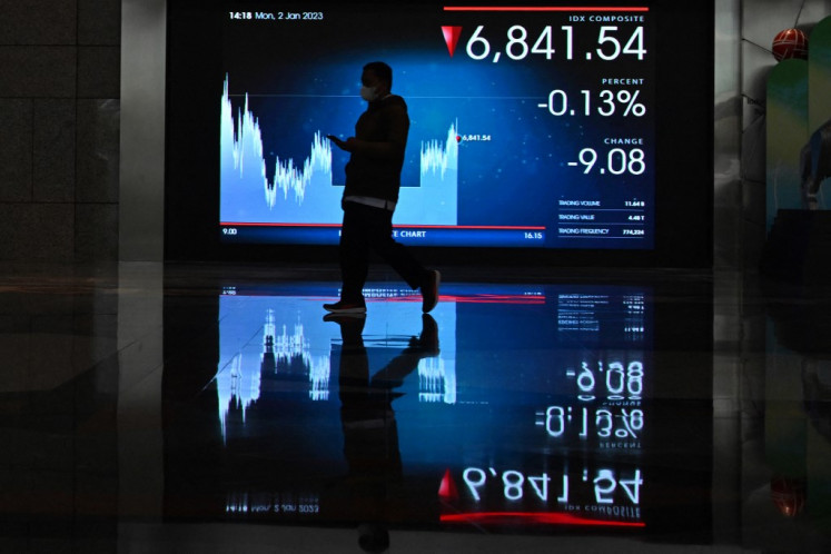 A man walks next to a screen at the Indonesia Stock Exchange in Jakarta on Jan. 2, 2023.