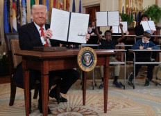 Joined by children seated at school desks, US President Donald Trump holds up the signed executive order to reduce the size and scope of the Education Department during a ceremony in the East Room of the White House on March 20, 2025 in Washington, DC. 