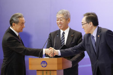 China's Foreign Minister Wang Yi (left) and South Korea's Foreign Minister Cho Tae-yul (right) shake hands as Japan's Foreign Minister Takeshi Iwaya (center) looks on during a joint press conference after their meeting during the 11th Trilateral Foreign Minister's Meeting (Japan-China-ROK) in Tokyo on March 22, 2025. The foreign ministers of Japan, South Korea and China agreed on March 22 that peace on the Korean peninsula is a shared responsibility, Seoul's Foreign Minister Cho Tae-yul said.