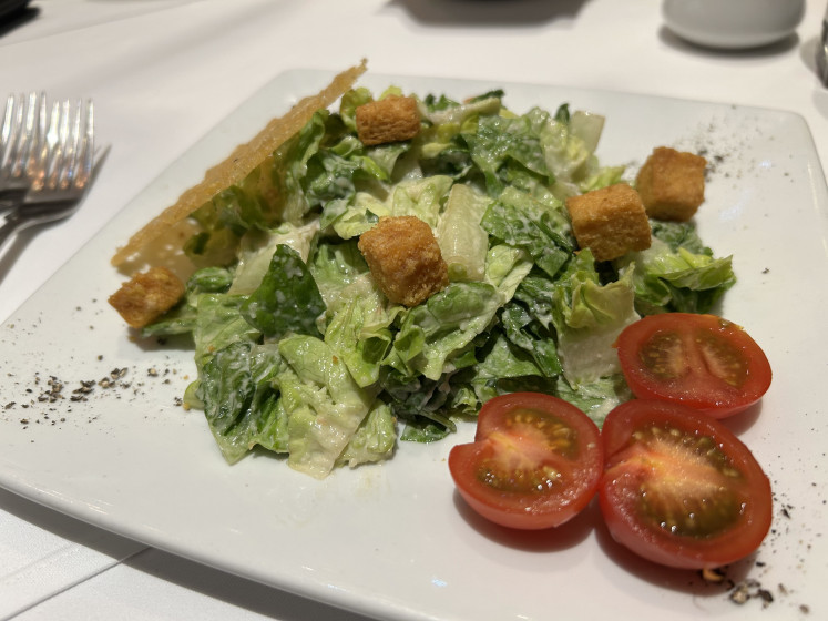Healthy palette cleanser: A plate of refreshing Caesar salad, sprinkled with a generous amount of garlic bread croutons.