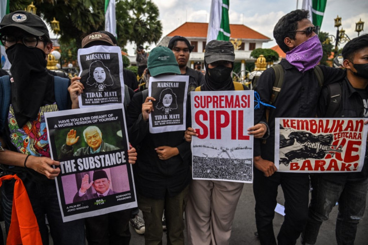 Students hold posters that read “return soldiers to the barracks“ (right) and “civilian supremacy“ (second right) during a protest against a revision to the Indonesian Military (TNI) Law in Surabaya, East Java on March 24.