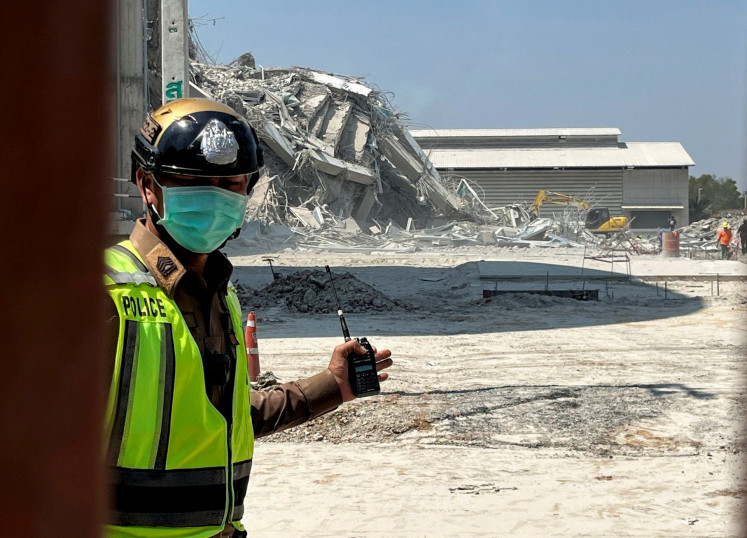 A police officer stands guard near a site of a collapsed building after the tremors of a strong earthquake that struck central Myanmar on Friday affected Bangkok, Thailand, March 28, 2025.