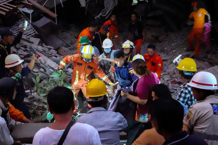 Rescue personnel carry a person out from the rubble of the building that collapsed following a strong earthquake, in Mandalay, Myanmar, March 29, 2025. 