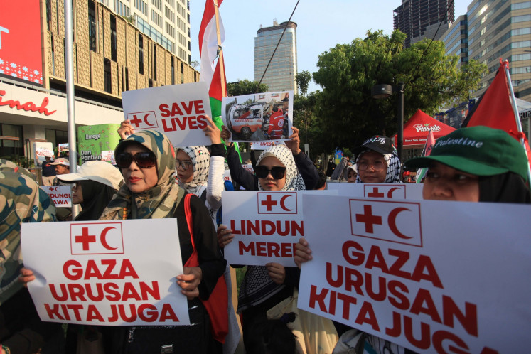 People hold posters that read “Gaza is also our business“  on April 7, 2025, during a peaceful rally supporting Palestinians in Gaza, in Jakarta. Medical workers, students and volunteers staged the rally to condemn the Israeli military's attack on medical personnel and hospitals in the Gaza Strip.