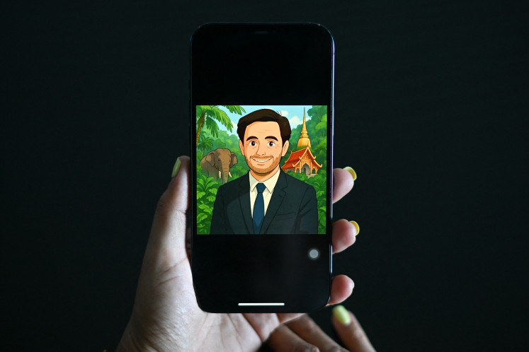 A woman looks at a Facebook user profile displaying an image generated by artificial intelligence AI in the style of Studio Ghibli animation on a mobile phone on April 2 in Bangkok. 