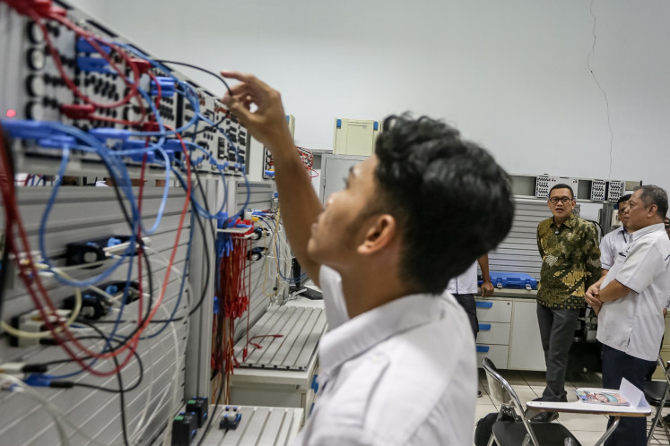 Migrant Workers Protection Minister Abdul Kadir Karding (second right, rear) watches as a trainee checks the wiring of a pneumatic machine on April 14, 2025, during his visit to the Surakarta Vocational Training and Productivity Center in the Central Java city. The center offers 12 training programs to the public, including people interested in working overseas as a migrant worker.