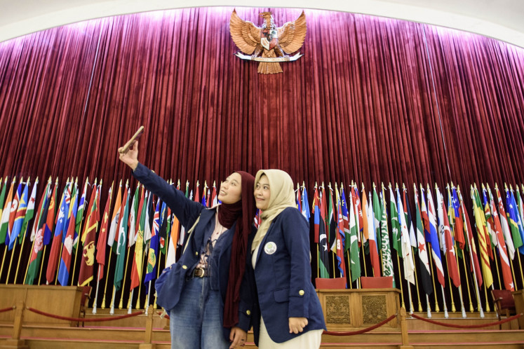 Reviving historic vision: Visitors take a selfie in front of Asian and African countries' flags on April 16 at the main hall of the Merdeka Building in Bandung, West Java. The building was the venue for the 1955 Asia-Africa Conference, also known as the Bandung Conference, where 29 Asian and African countries convened in the spirit of anti-colonialism.