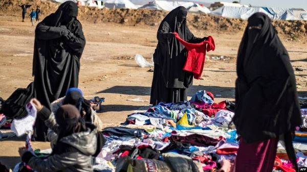 Worse for wear: Women in burka look through a pile of donated clothes on Jan. 14, 2020, outside al-Hol camp in al-Hasakeh, northeast Syria, which provides shelter for the stranded wives and children of former Islamic State fighters.