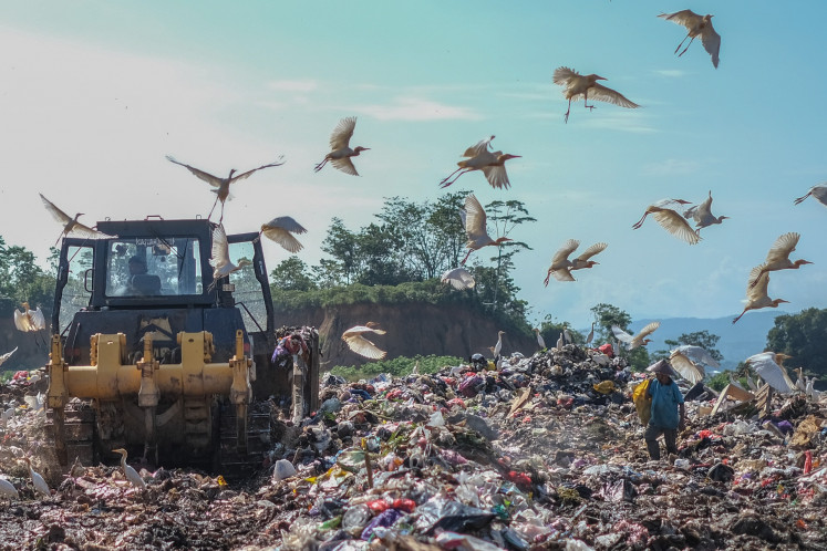 White storks fly away on April 14, 2025, from a heavy machine at the TPAS Puuwatu landfill in Kendari, Southeast Sulawesi. The Kendari Environment and Forestry Ministry has recorded that as of the first quarter of 2025, the volume of trash produced in the city reached 243 tonnes per day, an increase from the 210 tonnes per day recorded in the same period of last year.