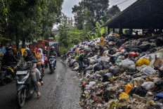 Awaiting proper management: Motorists ride next to a pile of trash on April 21 at the Cibeber integrated landfill in Cimahi, West Java. The Cimahi administration declared a state of emergency and suspended waste collection at its temporary landfills from April 21 to 27 as waste piled at the sites. 