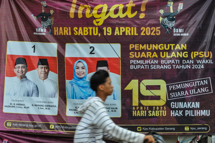 A motorist passes in front of a banner about the 2024 regional election revote in Serang regency, Banten on April 18, 2025. The regency was one of 24 regions ordered by the Constitutional Court in February to hold a rerun of the 2024 regional elections.