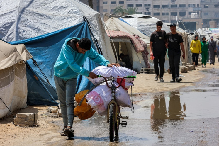 A boy pushes a bicycle loaded with sacks of food aid past tents in Gaza City on April 21, 2025. Israel on March 18 resumed its intense military offensive in the Palestinian territory after a ceasefire deal that came into effect on Jan. 19 fell apart two months later over differences regarding its next phase. 
