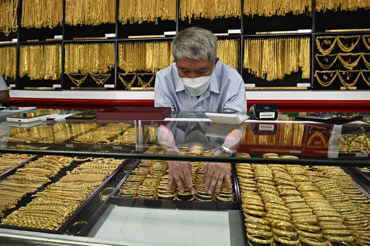 An employee of Hua Seng Heng arranges a tray of gold bracelets on April 9, 2025, at its shop in Chinatown, Bangkok.