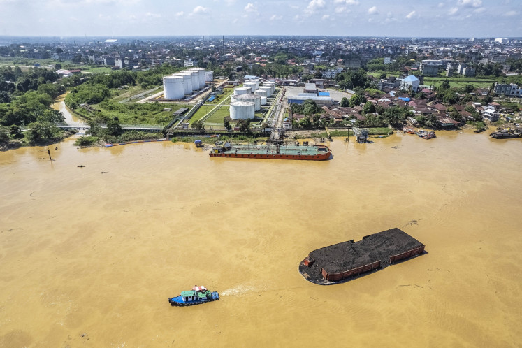 A tugboat pulls a coal barge through a section of the Batanghari River in Jambi on April 10, 2025.