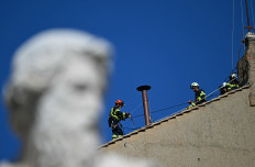 Firefighters install the chimney on the roof of the Sistine Chapel, with the statue of Saint Paul in the foreground, in The Vatican, on May 2, 2025. The conclave begins on May 7, when a record 133 cardinals -- those under the age of 80 who are eligible to vote -- will enter the Sistine Chapel to vote in secret for a new pontiff.