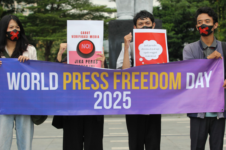 Several journalists hold banners during a protest to commemorate World Press Freedom Day in Surabaya, East Java, on May 2.