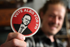 A bartender displays a campaign sticker ahead of a visit by Australia's re-elected Prime Minister Anthony Albanese to a local brewery for a beer with party workers in Sydney on May 4, 2025.