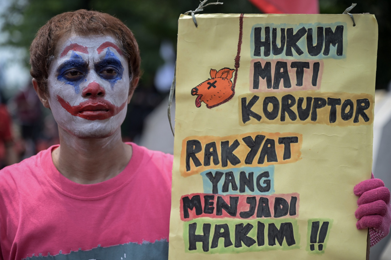 A rallygoer holds up a poster on May 1 that reads “Death to corruptors, let the people judge!“ during the Labor Day rally at the National Monument (Monas) complex in Jakarta.