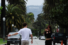 A person is recorded as the Hollywood Sign is seen in the background, after US President Donald Trump unveiled a 100 percent tariff on films made outside of the US, in Los Angeles, California on May 5, 2025.