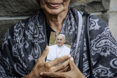 Cradled icon: A woman holds a picture of Pope Francis on Tuesday after visiting the Vatican Embassy in Jakarta. Catholics visited the embassy to pray for Pope Francis, who died at 88 on Monday, following a stroke after months of declining health.