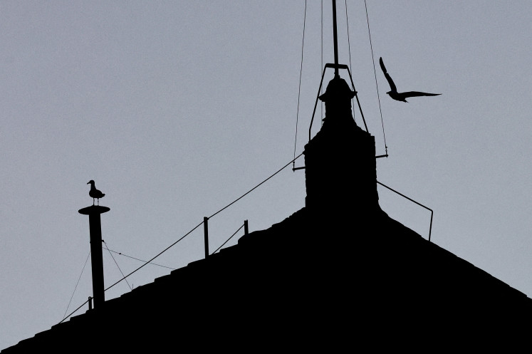 A bird sits atop the chimney on the Sistine Chapel roof, ahead of the conclave, at the Vatican, May 6, 2025.