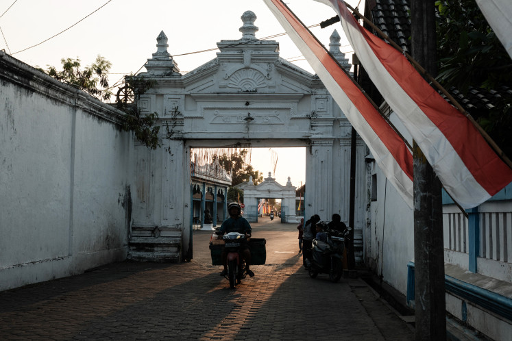 A person rides a scooter past the Surakarta Palace in Surakarta, Central Java, on July 30, 2024.