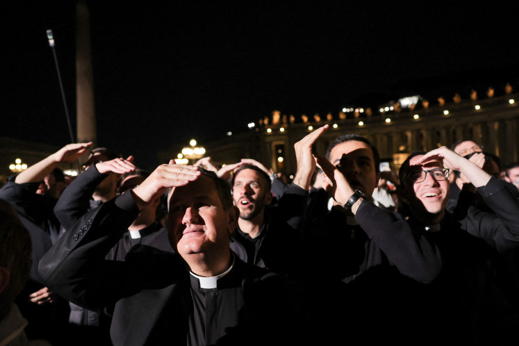  Faithful react to black smoke rising from the chimney on the Sistine Chapel indicating no decision has been made to elect a new pope, at the Vatican, May 7, 2025.